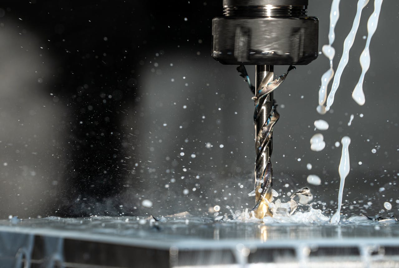 High-speed close-up of CNC drill bit in action with water splash for lubrication.